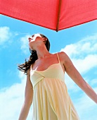 Woman in yellow dress standing under umbrella with eyes closed