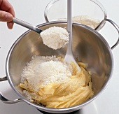 Grated cheese being added to mass for choux pastry, step 6