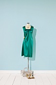 Green satin gown and necklace on mannequin