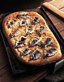 Pita bread with sardines and onions in baking tray