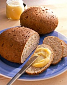 Close-up of two loaves of nut bread, slice of bread with honey and knife