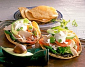 Tostadas with lettuce, avocado, feta and chicken meat on tray