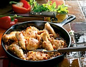 Close-up of chicken with peppers, ham and tomatoes in frying pan