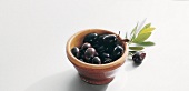 Black olives in bowl on white background