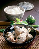 Duck curry with coconut milk in serving dish and sticky rice in bowl