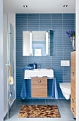 Blue tiled bathroom with washbasin and towel rail