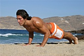 A man doing pushups on the beach