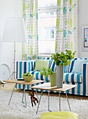 Wohnzimmer mit blau-weiss gestreiftem Sofa und Vorhang mit Blättermotiv