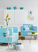 Two turquoise and blue patterned armchairs and side tables in front of white cupboard