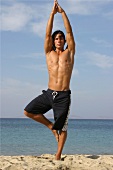 Man doing yoga on the beach (The Tree)