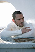 Man in white turtleneck sweater smoking a cigarette