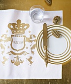 Golden-white plates on table mat with glass on side