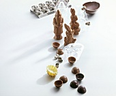 Various chocolate figures and chocolate mould on white background