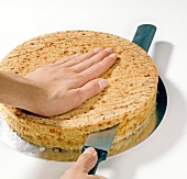 Cake being cut into half for preparation of biscuit, step 1