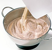 Close-up of cocoa dough being stirred in pan for preparation of chocolate, step 3