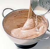 Close-up of milk being poured in mixture for preparation of chocolate, step 4