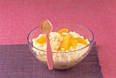 Close-up of orange rice pudding and one tablespoon filled with cinnamon powder on bowl