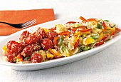Close-up of rice and vegetable salad with stewed tomatoes and sesame seeds in dish