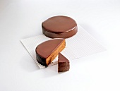 Whole, halved and piece of sacher torte on white background