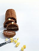 Sliced ginger chocolate cake with ginger pieces on white background