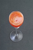 Glass of blood orange mimosa on gray background
