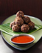 Beef and coconut balls with a tomato dip on a banana leaf