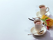 Two chocolate drinks in cup with chilli pepper and honeycomb on white background