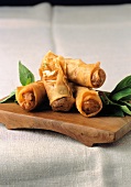 Spring rolls with leaves on wooden board, Indonesia
