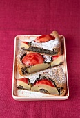 Three pieces of red pear cake with poppy seeds and icing sugar in serving plate