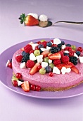 Berry sour cream cake with strawberries and raspberries on purple plate