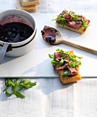 Crostini with roast beef and spicy cherry jam on white board