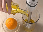 Oil being poured in glass with hand blender for preparation of orange aioli, step 3