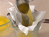 Liquid butter being passed through sieve with cloth to prepare hollandaise sauce, step 2