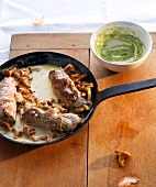 Bowl of thyme pesto and veal rolls with chanterelles in pan