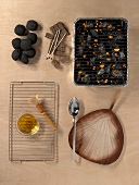 Grill briquette, brush, oil bowl and grill lighter on wooden background