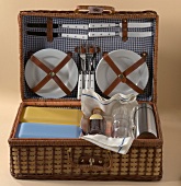 Open picnic basket with plates, cutlery and glasses