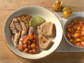 Bowl of physalis salsa and aloe lime turkey steaks with physalis salsa and bread on plate