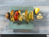Skewer with potato wedges and peppers on square shaped plate