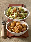 Two bowls of caesar's salad with croutons and red potato salad