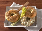 Two sesame bagel, one with egg salad and other being cut into half