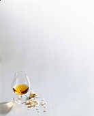 Glass of cognac, chopped onions, garlic and basil on white background