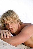 Portrait of handsome blond man lying on the beach