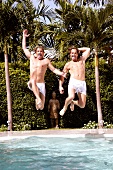 Men with shirtless jumping into the pool with palm trees in background