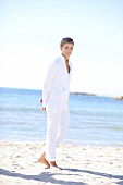 Frau in weißer Kleidung barfuß am Strand