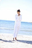 Frau am Strand trägt weiße Hose und weiße Strickjacke