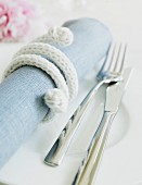 Napkin wrapped with cord and cutlery on plate