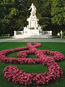 Pink begonia arranged in shape of Treble clef against Mozart monument