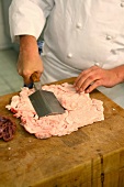 Chef flattening calf's kidney fats on wooden board