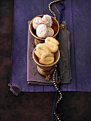 Two bowls of S-shaped butter biscuits and almond cookies with powdered sugar