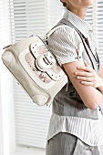 Woman wearing formals carrying cream coloured handbag with snakeskin detail on it